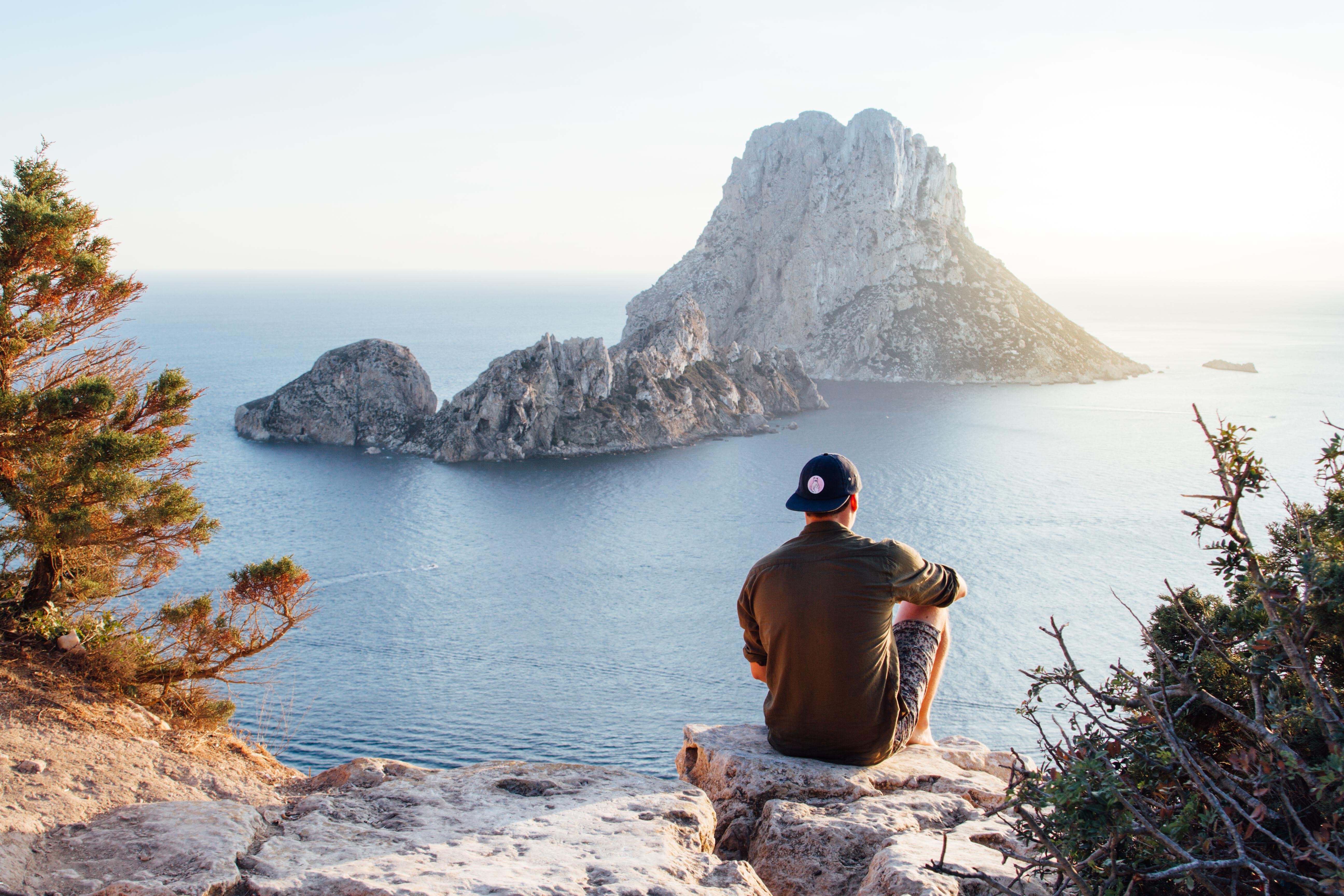 A photograph of a man looking at the ocean from a view